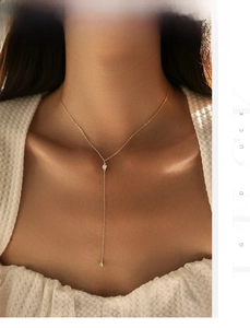 Close-up of elegant gold Y-shaped necklace with sparkling zircon drop on a female model