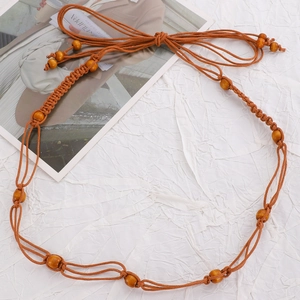 Detail of bohemian waist chain featuring brown braided rope and yellow wooden beads