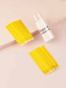 Macro shot of yellow disposable micro applicators on pink geometric stands for lash cleaning