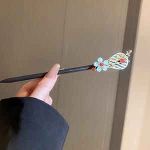 Macro detail of Chinese hair stick with blue flower and tassel on dark wooden rod