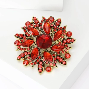 Detail view of a vintage floral brooch with large red crystal and gold plating