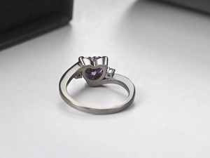 Detail view of heart-shaped purple zircon ring with silver-tone band on black jewelry box
