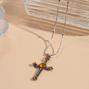 Macro detail of gothic cross necklace with yellow gemstone and gunmetal snake chain