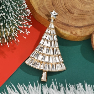Macro view of a gold Christmas tree brooch with clear crystals on a festive background