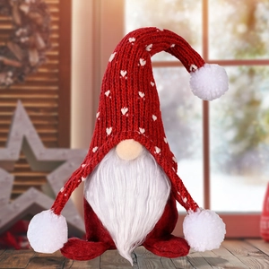 Weihnachtswichtel mit roter Strickmütze und Herzmuster auf einem rustikalen Holztisch