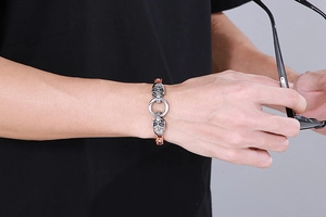 Close-up of punk style skull bracelet with orange accents on man's wrist