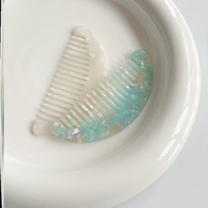 Mini acetate hair combs in pearlescent white and turquoise marble pattern in ceramic bowl