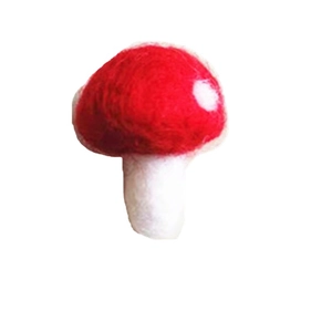 Handmade wool felt red mushroom Christmas ornament with white dots on a plain background