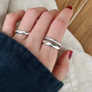 Close-up of minimalist silver ring set featuring smooth bands and a twisted rope texture