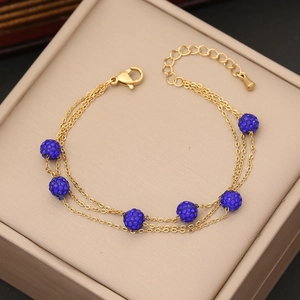 Dettaglio di catene triple dorate con sfere di strass blu e chiusura a moschettone