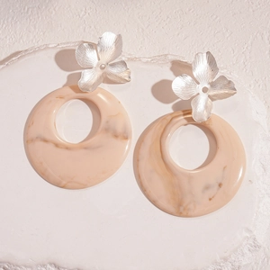 Macro shot of resin flower earrings with marble texture and brushed metal petals