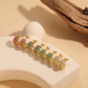 Detail view of multi-layer C-shaped earrings with colorful cubic zirconia in gold settings