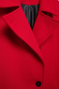 Close-up of vibrant red wool blend fabric texture and notched lapel on long winter coat