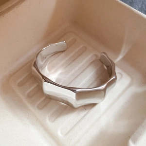 Detailed close-up of a silver acrylic open bangle with geometric faceted wave design