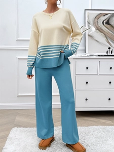 Detailed close-up of a striped knit sweater and wide-leg trousers on a model in a cozy room