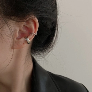 Close-up of silver layered ear cuffs with irregular texture and chain design on model