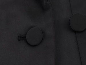 Dettaglio macro del tessuto twill nero e bottoni rivestiti in tessuto strutturato