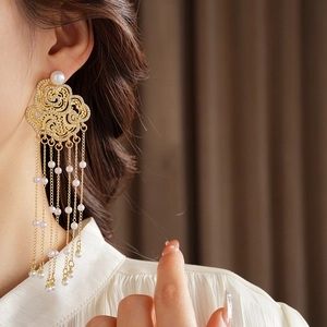 Detailed view of gold cloud earrings with pearl tassels on model for a vintage look