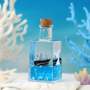 Close-up of a glass nautical drifting bottle with a pirate ship and blue fluid on beach