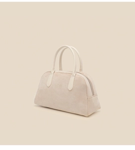 Macro detail of beige suede Boston bag featuring smooth leather handles and a zipper closure