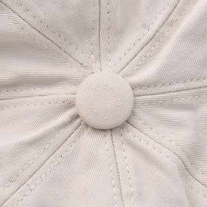 Close-up of the beige vintage beret crown showing twill cotton texture and top button