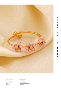 Detailed macro of gold flower bangle featuring pink beaded petals on smooth metal