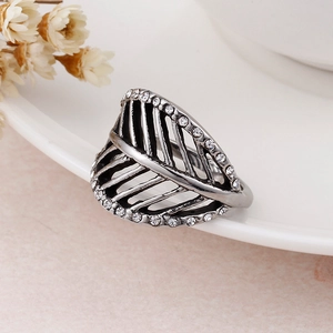 Macro shot of gun black feather ring with sparkling rhinestones on white ceramic