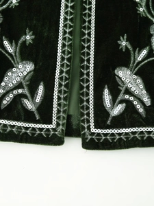 Detailed macro view of dark green velvet fabric with white floral embroidery and sequins