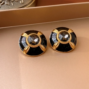 Detailed macro view of vintage round black enamel earrings with gold textured plating