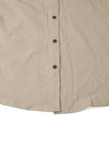 Close-up detail of beige linen shirt fabric texture and brown buttons on the curved hemline