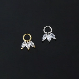 Close-up of gold and silver charms with marquise-cut zircons in a fan-shaped design