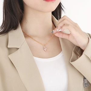 Detail of pink conch shell pendant on a gold necklace with pink bead accents