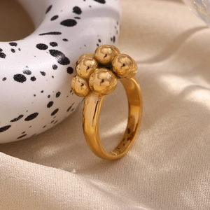 Close-up of a 18K gold plated bubble ring with round spheres on beige silk fabric