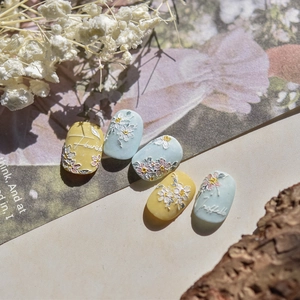 Detailed macro of 3D embossed nail art stickers featuring white floral patterns and cursive text