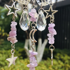 Detail of silver suncatcher with purple stones and faceted crystal prisms in outdoor light