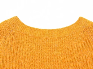 Detail of ribbed crew neck and textured knit fabric on an orange pullover sweater