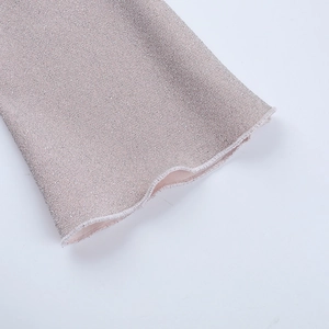 Detail of pink glitter fabric with elegant ruffled edges on a long sleeve dress