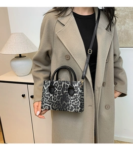 Leopard print handbag with black and white pattern shown as a crossbody bag on camel coat