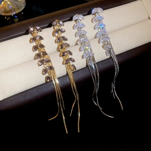 Detailed view of silver and gold leaf-shaped tassel earrings with zircon in a jewelry box