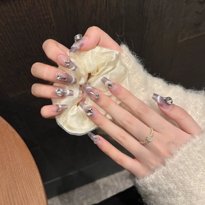 Purple cat-eye gradient press-on nails with heart-shaped rhinestones and metallic accents
