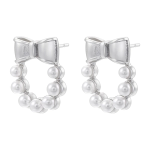 Close-up of silver bow stud earrings with a circular white pearl wreath detail