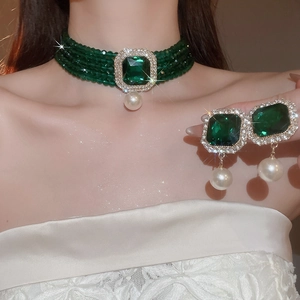Detail of emerald green crystal pendant on multi-layer pearl necklace with matching earrings