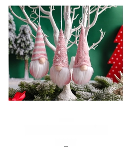Detailed view of three pink knitted Christmas gnomes hanging on a white branch
