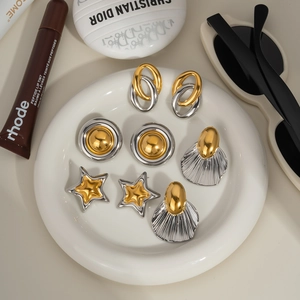 Detailed view of four pairs of vintage two-tone gold and silver earrings on a ceramic tray