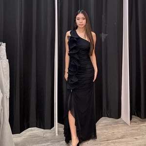 Détail d'une robe de soirée noire asymétrique avec des volants et une fente haute à la jambe