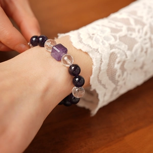 Détail macro du bracelet en cristal blanc et améthyste violette sur un poignet avec dentelle