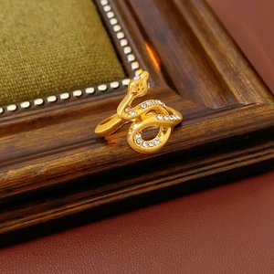 Macro detail of a gold snake ring with pavé diamonds on a vintage wooden texture background