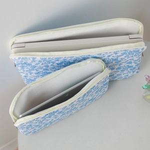 Detailed view of quilted floral laptop sleeves with thick padding and white zippers