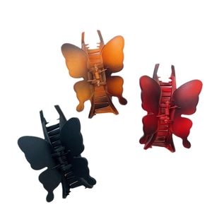 Three elegant butterfly hair claws in black, brown, and red gradient on a white background
