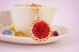 Close-up of red rhinestone ball keychain with gold plating for handbags